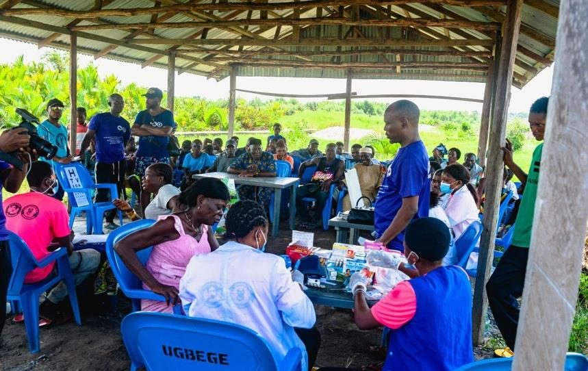 Medical outreach in a riverine community, patients seated under a shelter